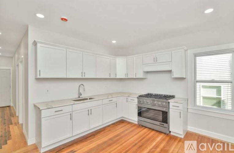 A kitchen with white cabinets and a wooden floor.