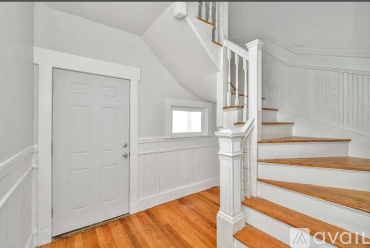 A staircase with white railings and wooden steps leads up to a window.