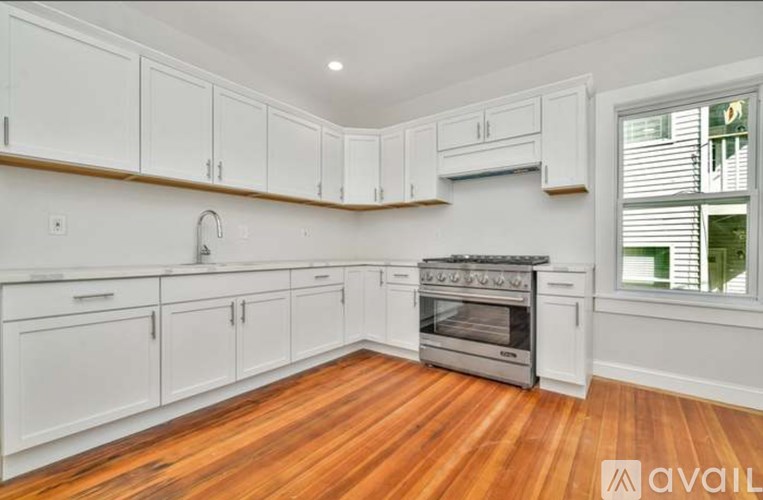 A kitchen with white cabinets and a wooden floor.