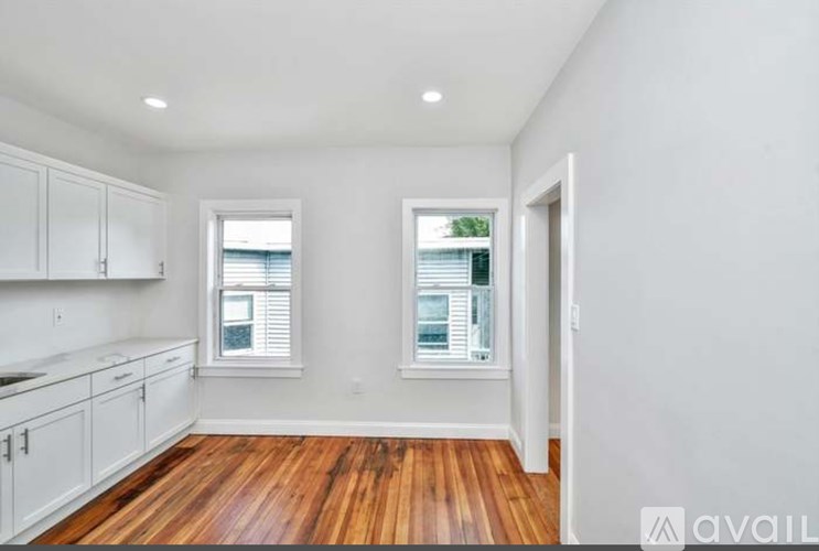 A kitchen with white cabinets and wooden floors.