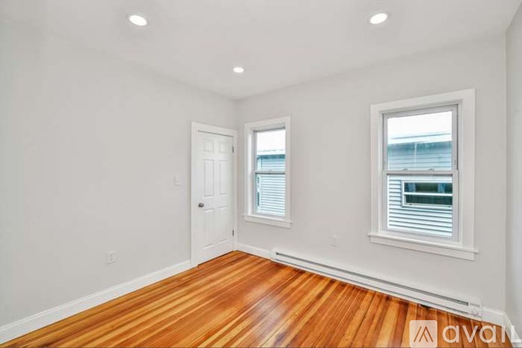 A room with wooden floors and two windows.