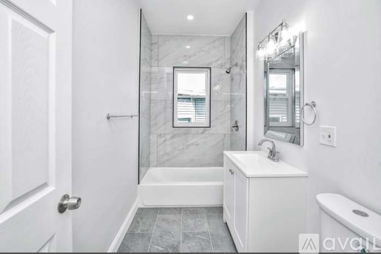 A white bathroom with a marble shower and a white vanity.