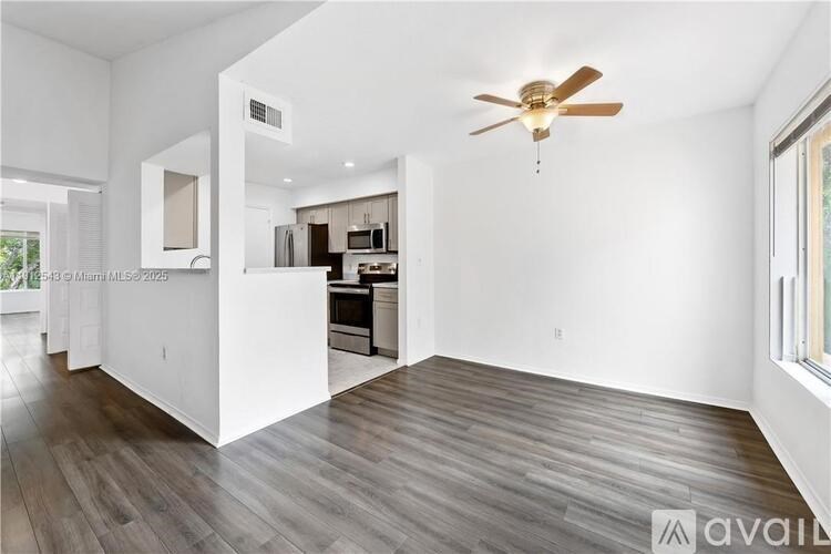 A spacious room with a ceiling fan and wooden flooring.