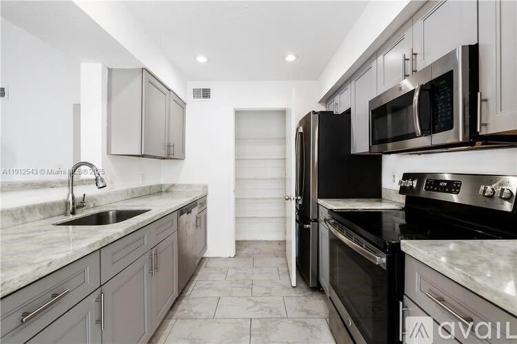 A kitchen with black appliances and marble countertops.