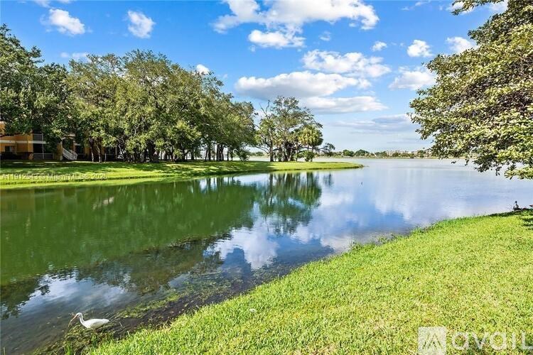 A serene lake surrounded by lush greenery under a clear blue sky.