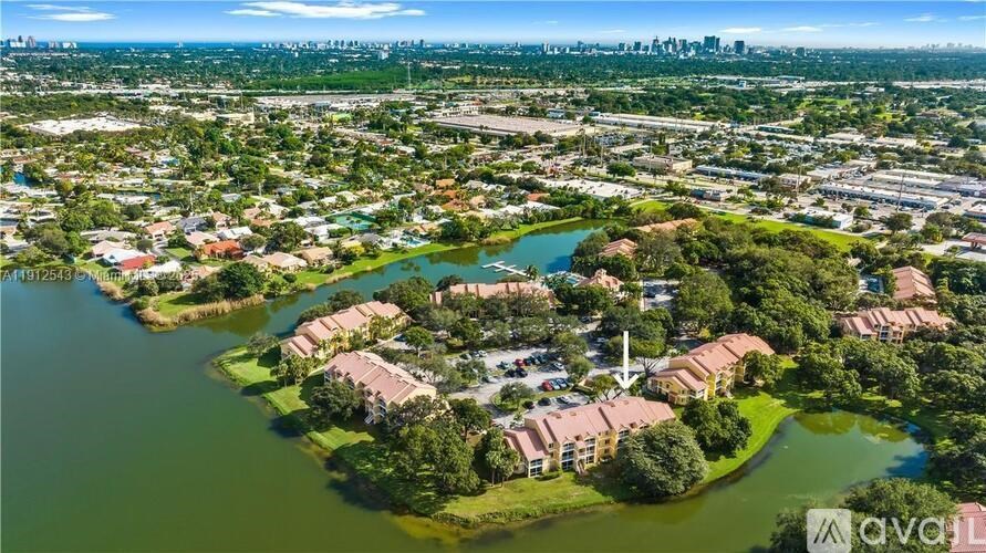 An aerial view of a residential area with a lake in the foreground and a city skyline in the distance.