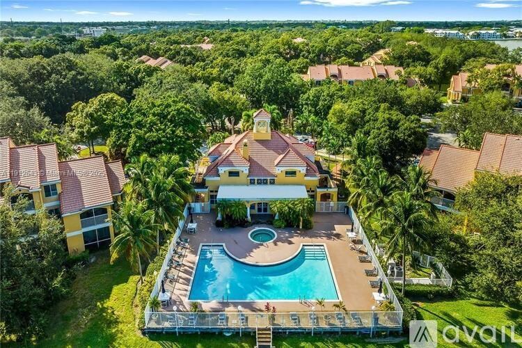 A large house with a pool in the middle of a lush green area.
