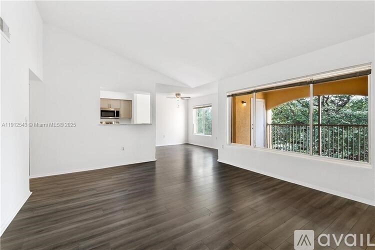 A spacious room with wooden flooring and white walls.