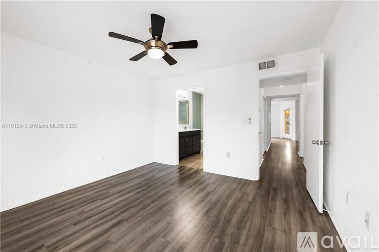 A spacious room with a ceiling fan and wooden flooring.