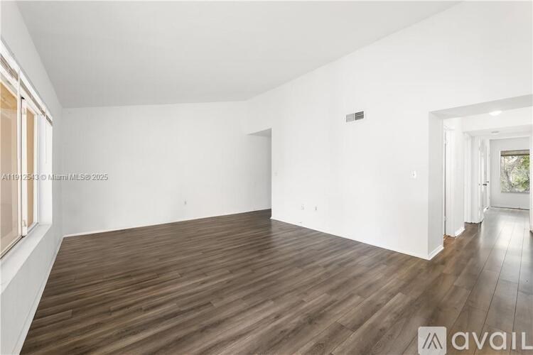 A spacious room with wooden flooring and white walls.
