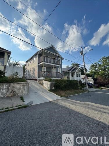 A house with a white fence is situated on a street with a clear sky above.