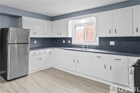 A kitchen with white cabinets and a stainless steel refrigerator.