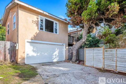 A house with a white garage door and a tree in front.