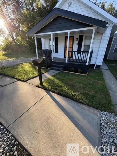 A small white house with a black roof and a porch.