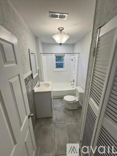 A white bathroom with a toilet, sink, and shower.
