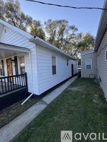 A white house with a black railing and a green lawn.
