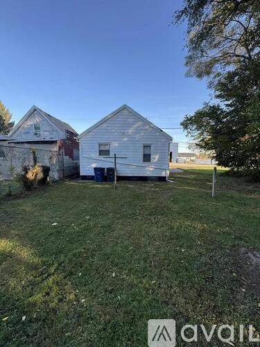 A white house with a blue garage door is situated in a grassy area.