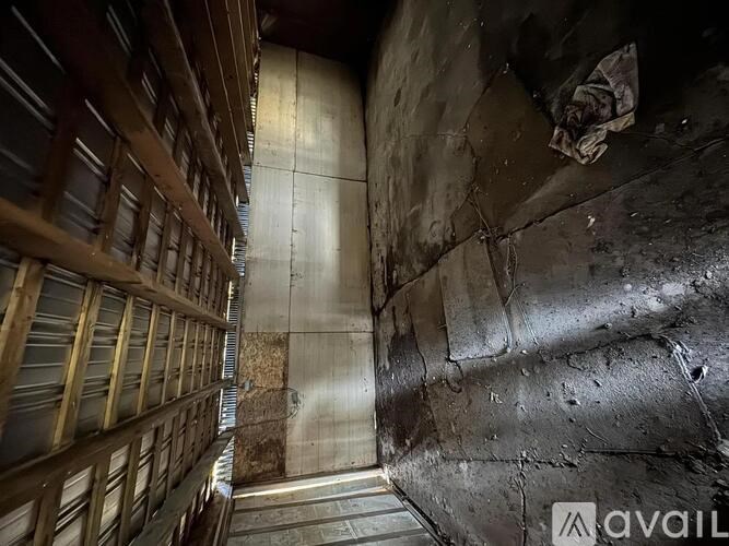 A dirty, dark industrial hallway with a metal staircase on the left.