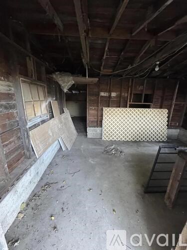 A room with wooden walls and ceiling, a window, and a patterned mat on the floor.