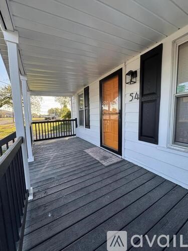 A porch with a wooden floor and a black railing.