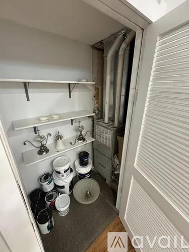 A small, white, and clean kitchen pantry with a white door and a white shelf.