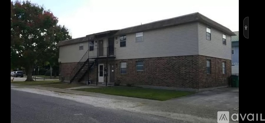 A two-story apartment building with a garage door and a staircase leading to the second floor.