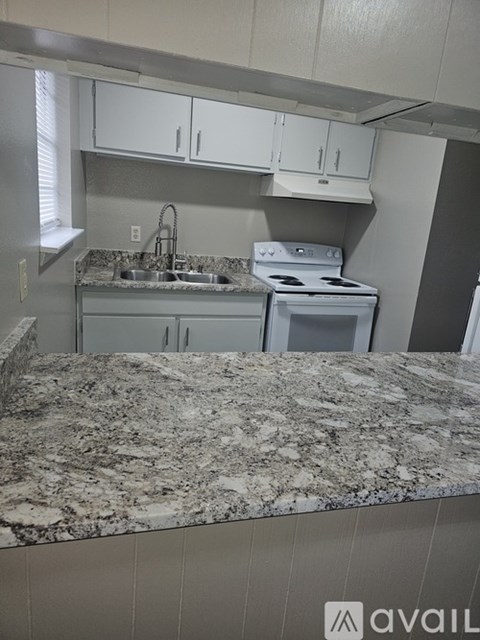 A kitchen with granite countertops and white cabinets.