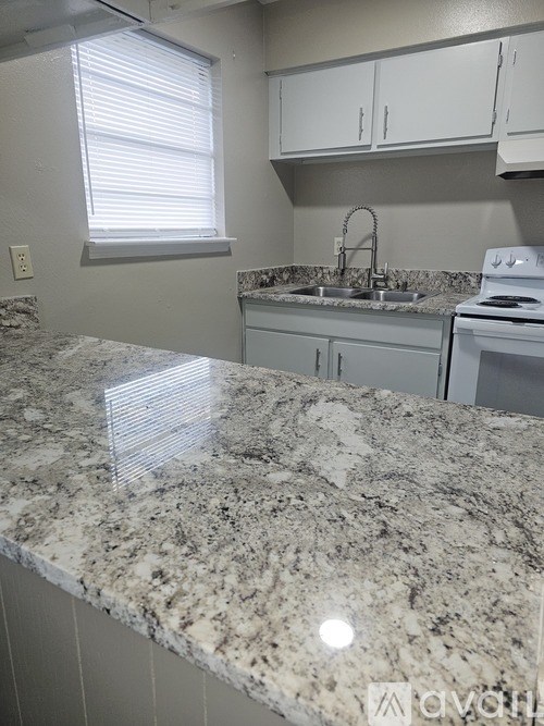 A kitchen with granite countertops and white cabinets.