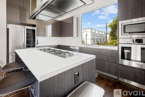 A modern kitchen with a white countertop and stainless steel appliances.