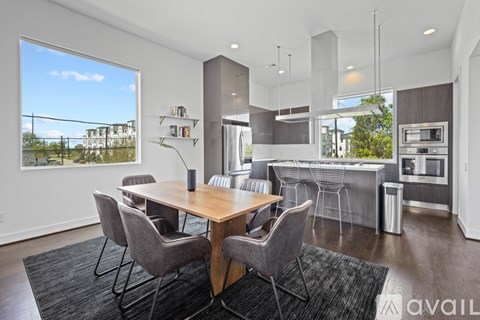 A modern kitchen with a dining table and chairs in the foreground.
