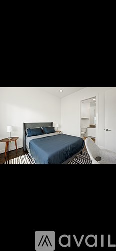 A bedroom with a bed, nightstand, and chair.