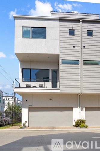 A modern two-story house with a balcony on the second floor.
