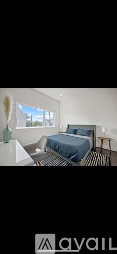 A bedroom with a bed, a chair, and a window.