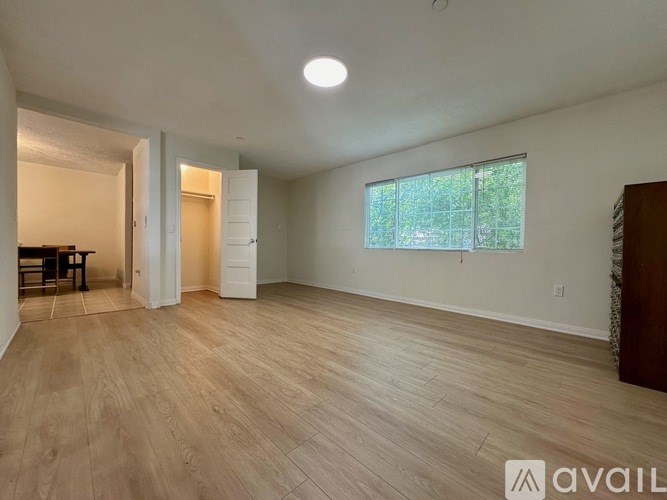 A spacious room with wooden flooring and a large window.