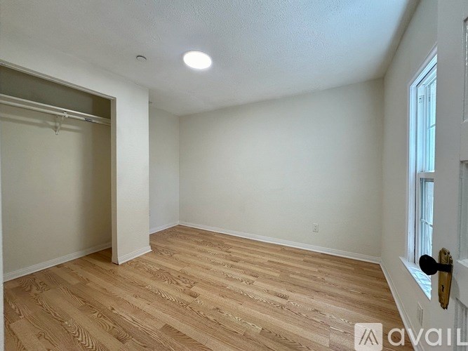 A room with wooden flooring and white walls is available for rent.