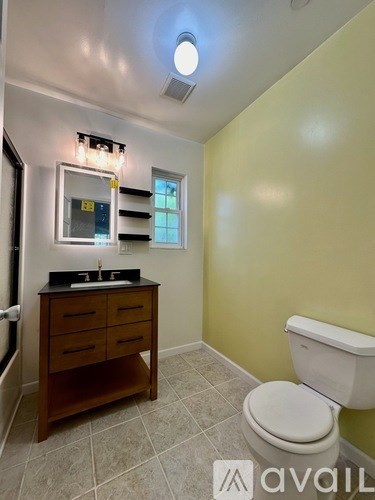 A bathroom with a toilet, sink, and mirror.