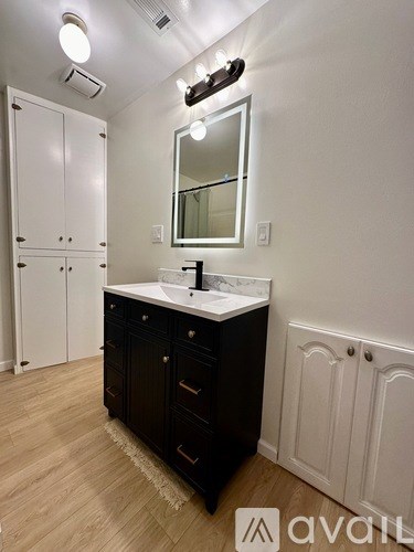 A bathroom with a sink, mirror, and wooden floors.