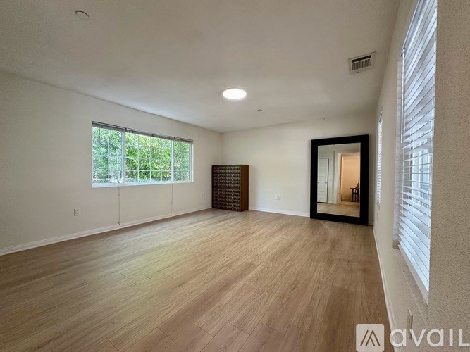 A spacious room with wooden flooring and a large window.