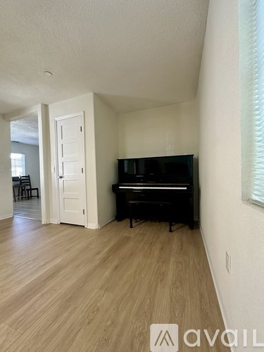 A black piano is in a room with a white door.