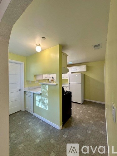 A kitchen area with a sink, cabinets, and a trash can.