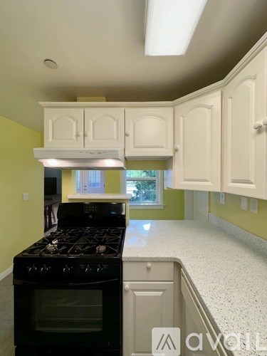 A kitchen with a black stove top oven and white cabinets.