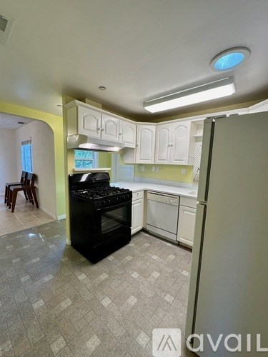 A kitchen with a black stove top oven and white cabinets.