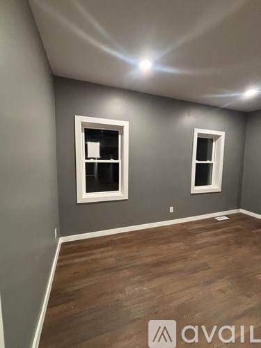 A room with wooden floors and two windows.