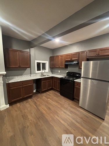 A kitchen with wooden cabinets and a stainless steel refrigerator.