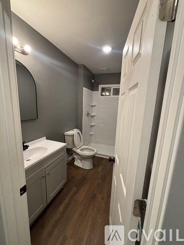A bathroom with a toilet, sink, and mirror.