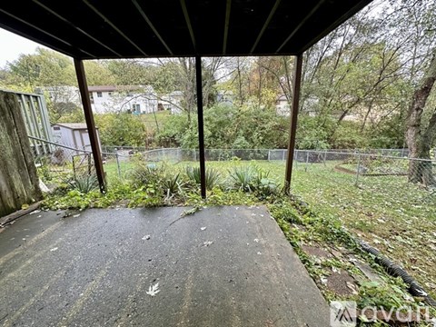 A concrete patio with a metal fence and trees in the background.