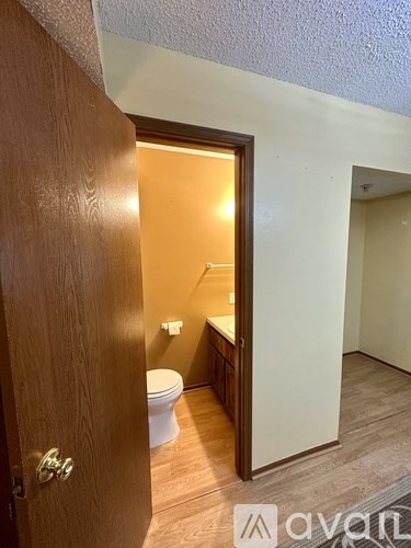 A wooden door opens to a bathroom with a toilet and sink.