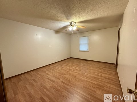 A room with wooden flooring and a ceiling fan.