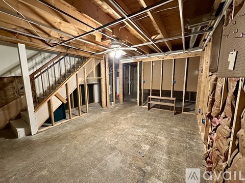 A room under construction with exposed ceiling beams and unfinished walls.