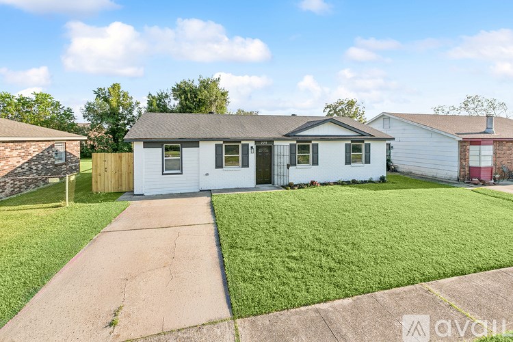 A white house with a grey roof and a brown fence.